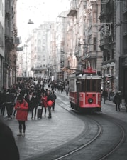 people walking on sidewalk near red tram during daytime