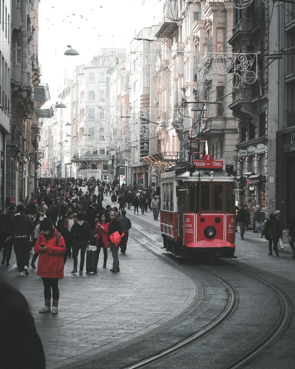 people walking on sidewalk near red tram during daytime