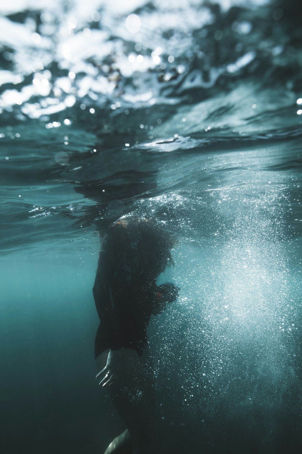 person in black wet suit in water