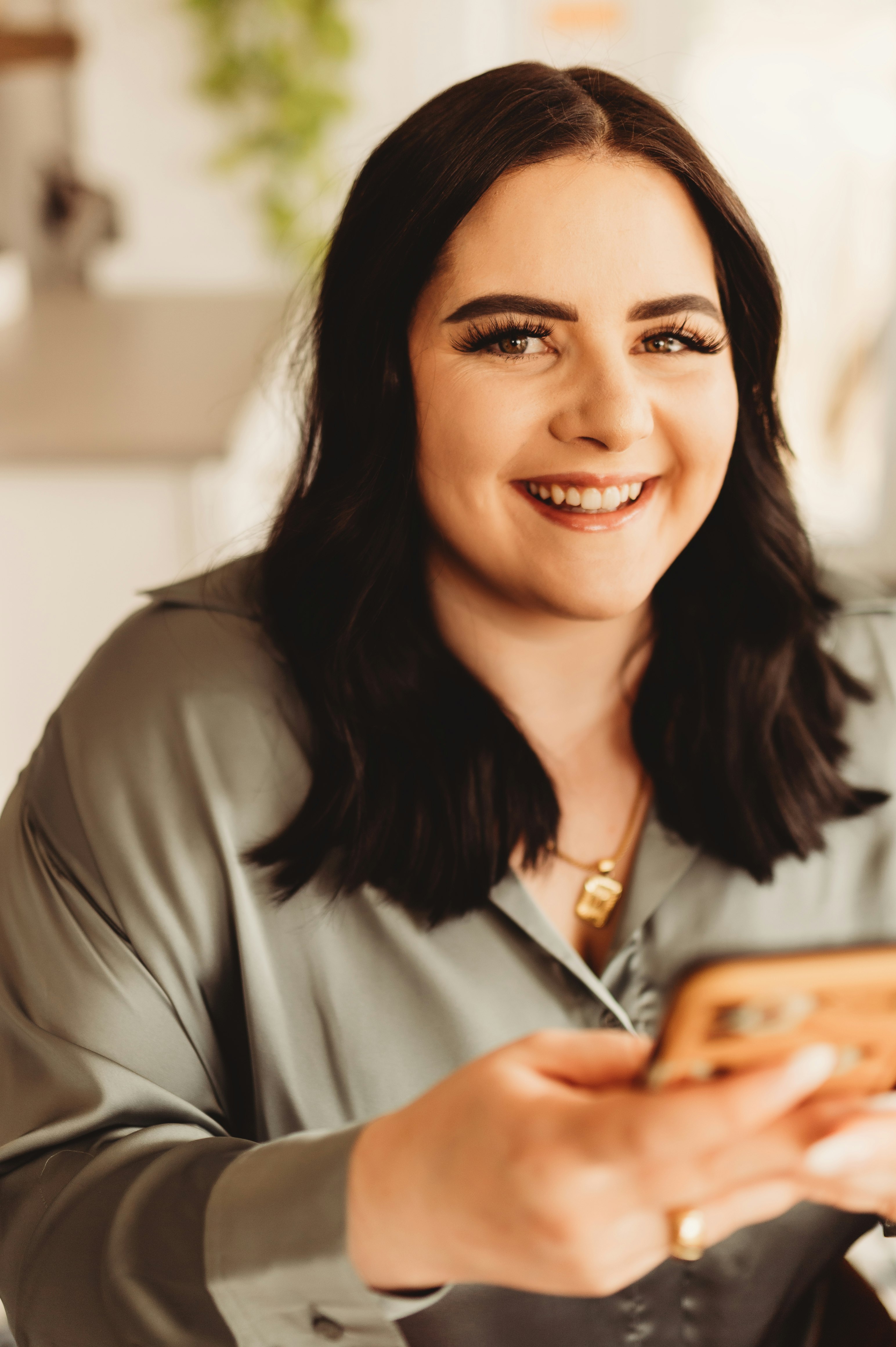 smiling woman in gray blazer holding smartphone