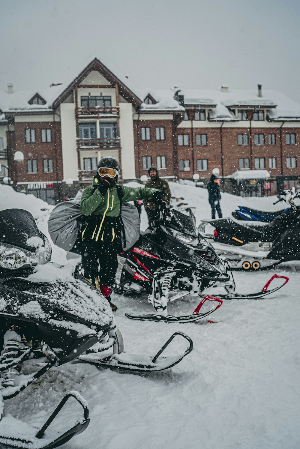 man in black jacket riding on black motorcycle on snow covered road during daytime