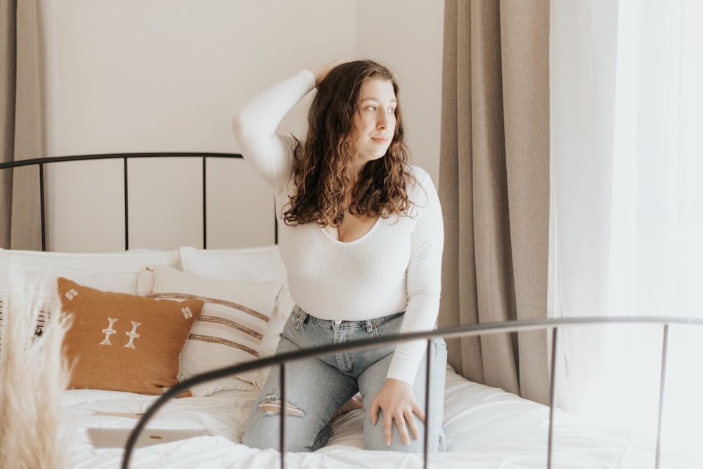 woman in white long sleeve shirt sitting on bed