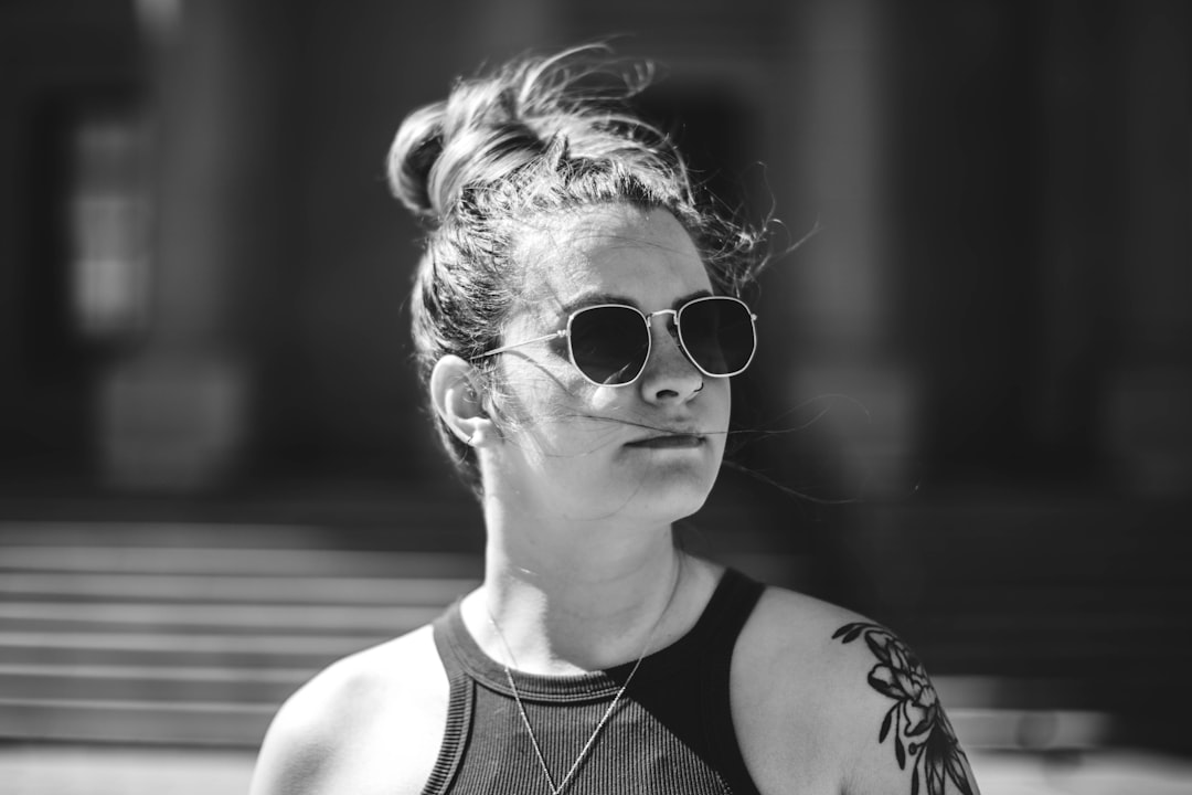 grayscale photo of woman in tank top wearing sunglasses