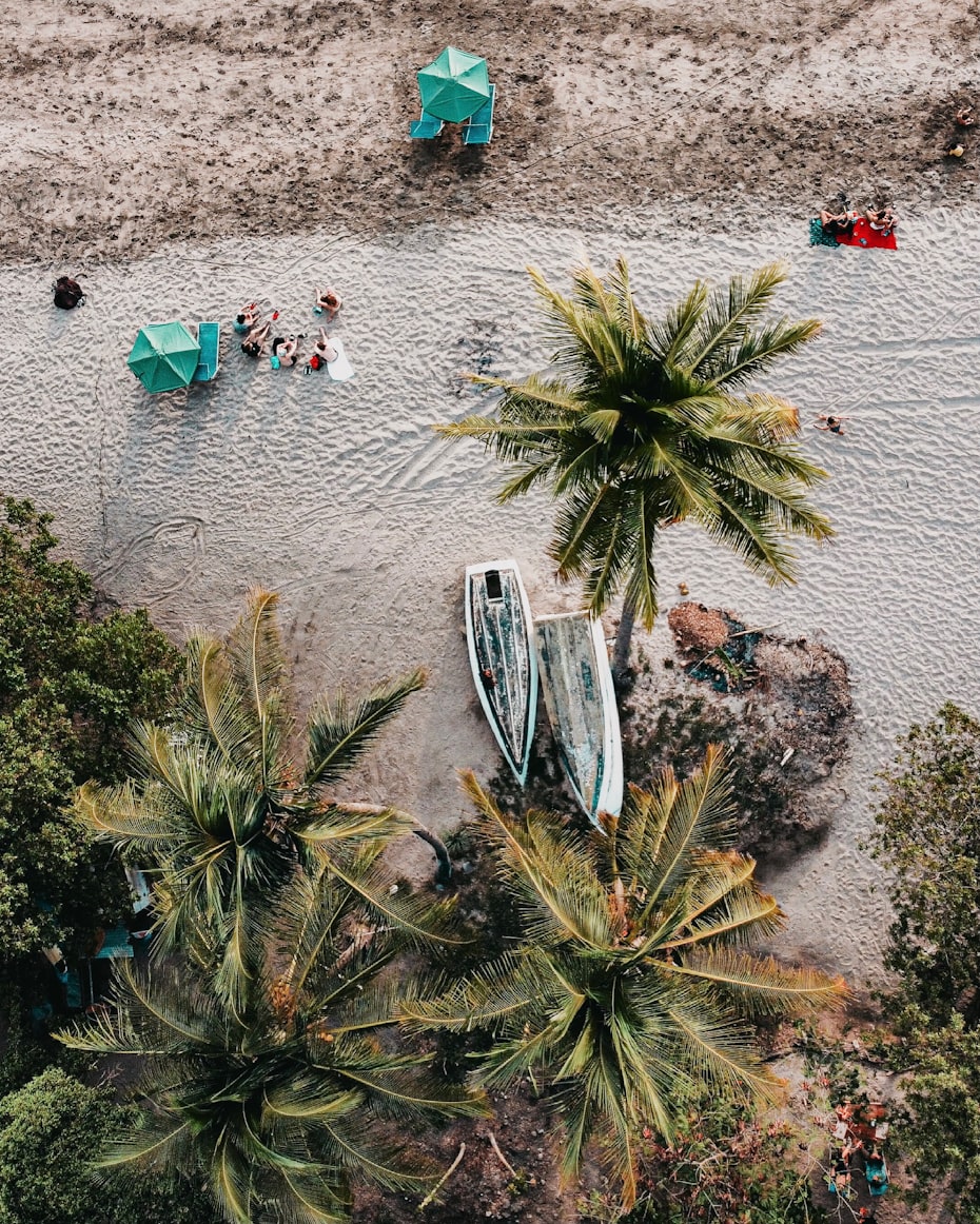 Birds eye view of beach with trees, boats, and people in Nicoya, Costa Rica.