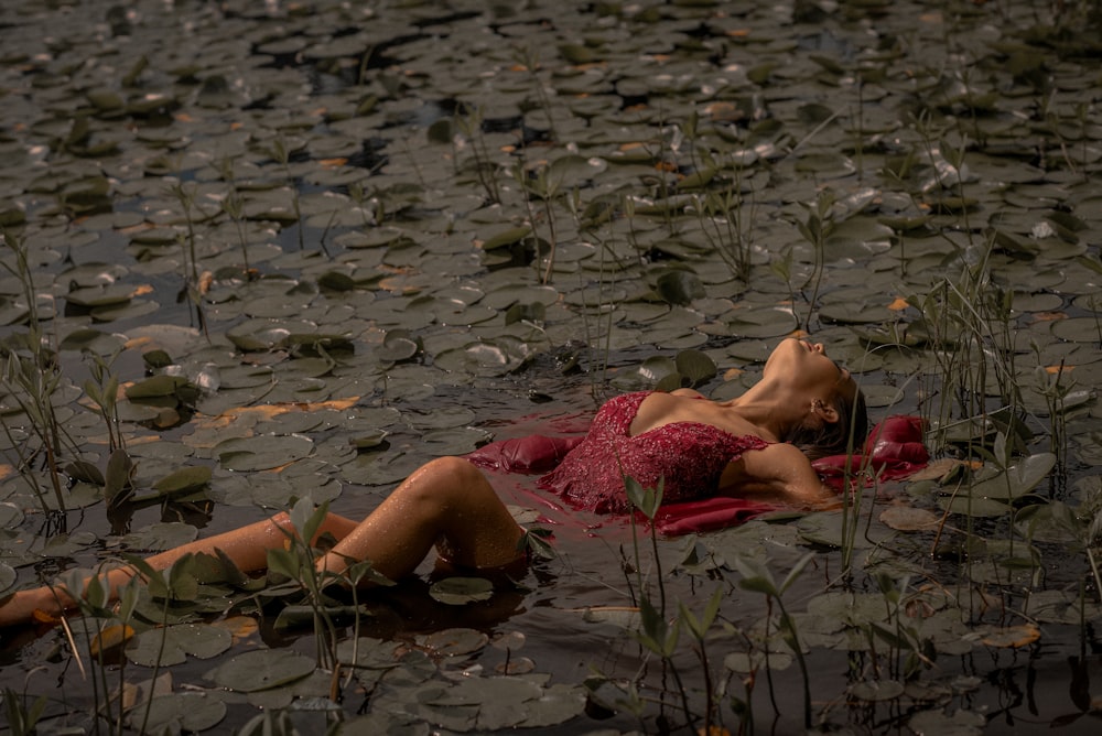 woman lying on pink textile on water