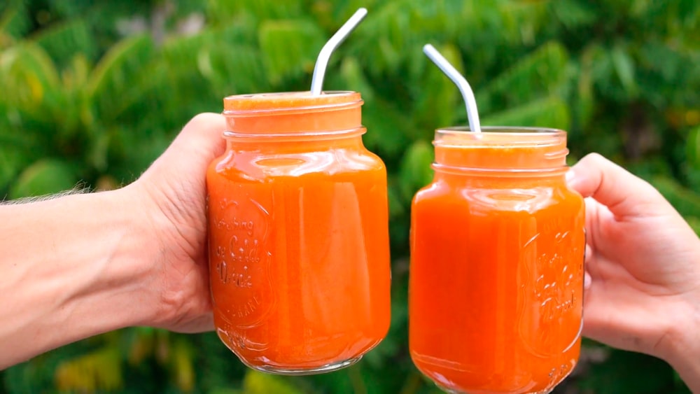 person holding orange liquid in jar