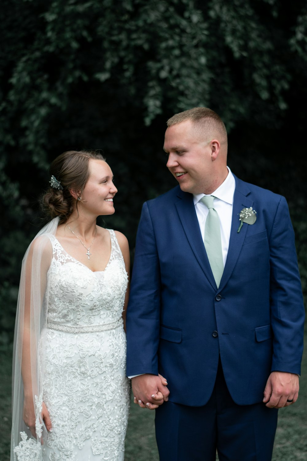 man in blue suit jacket and woman in white floral wedding dress