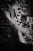A pair of legs wearing white socks is positioned against a collage-like background featuring various retro elements such as a Coca-Cola sign, a license plate, and the words 'The End'. The image has a vintage and artistic feel, rendered in black and white.