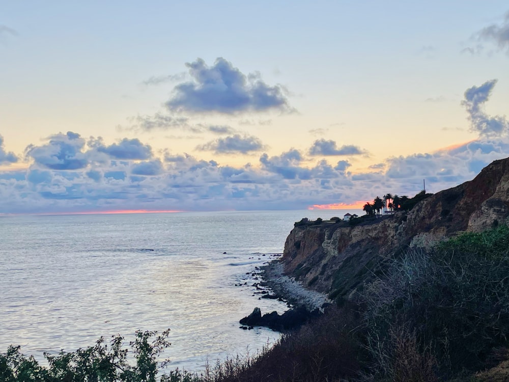 silhouette of people standing on cliff by the sea during sunset