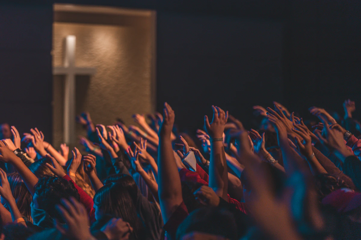 People worshipping with hands raised in front of the stage
