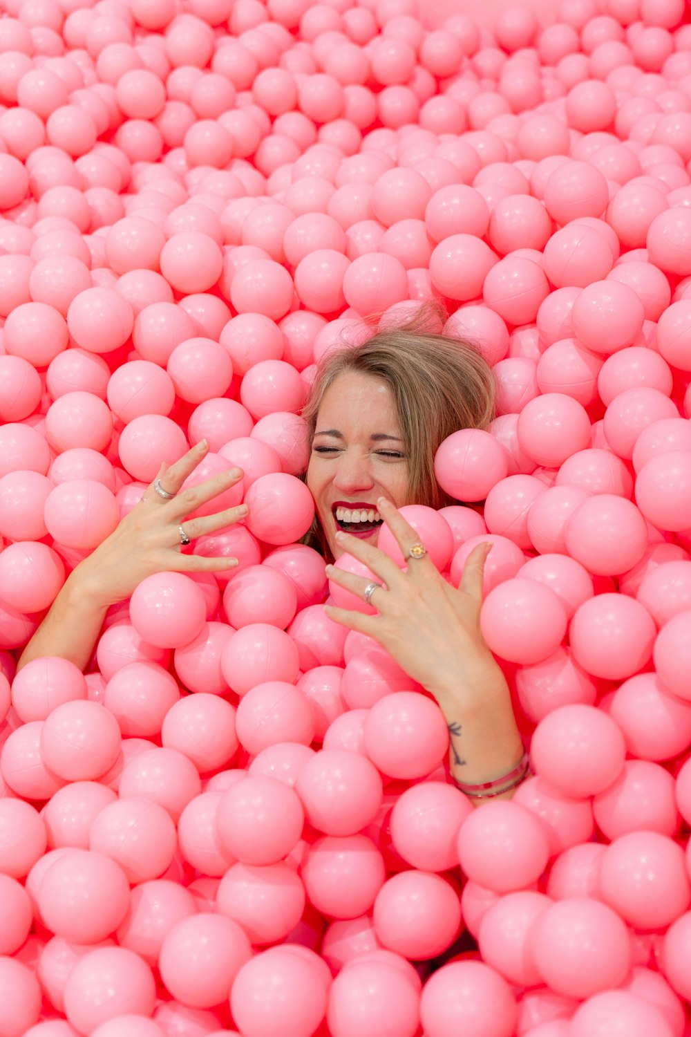 mulher de cabelos loiros deitada em bolas redondas cor-de-rosa