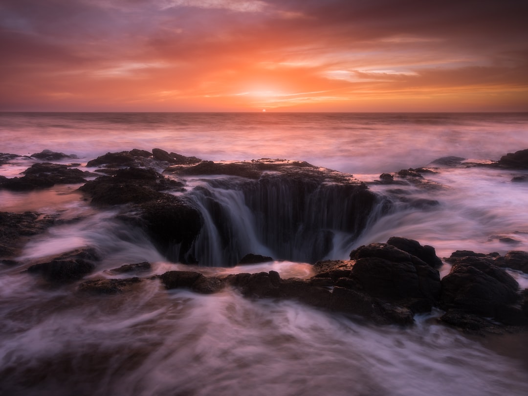 water falls under gray sky during sunset