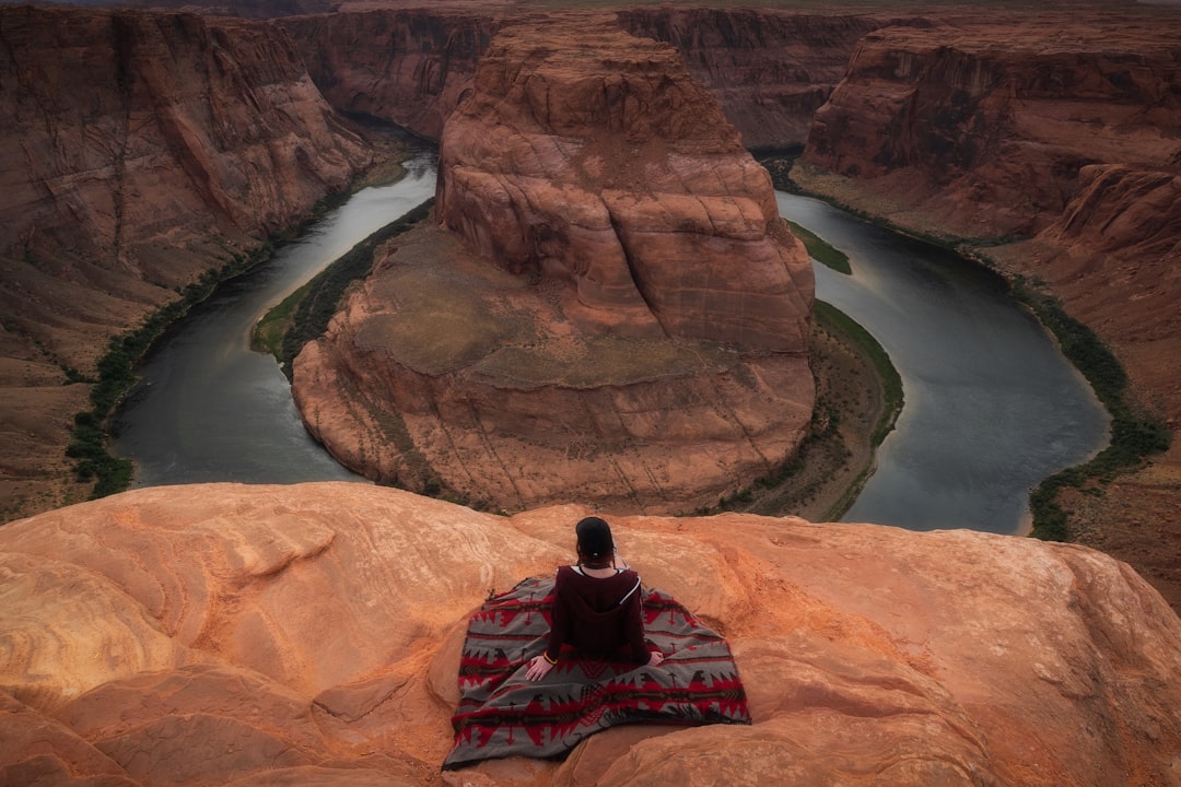 man in black and red plaid shirt sitting on rock formation