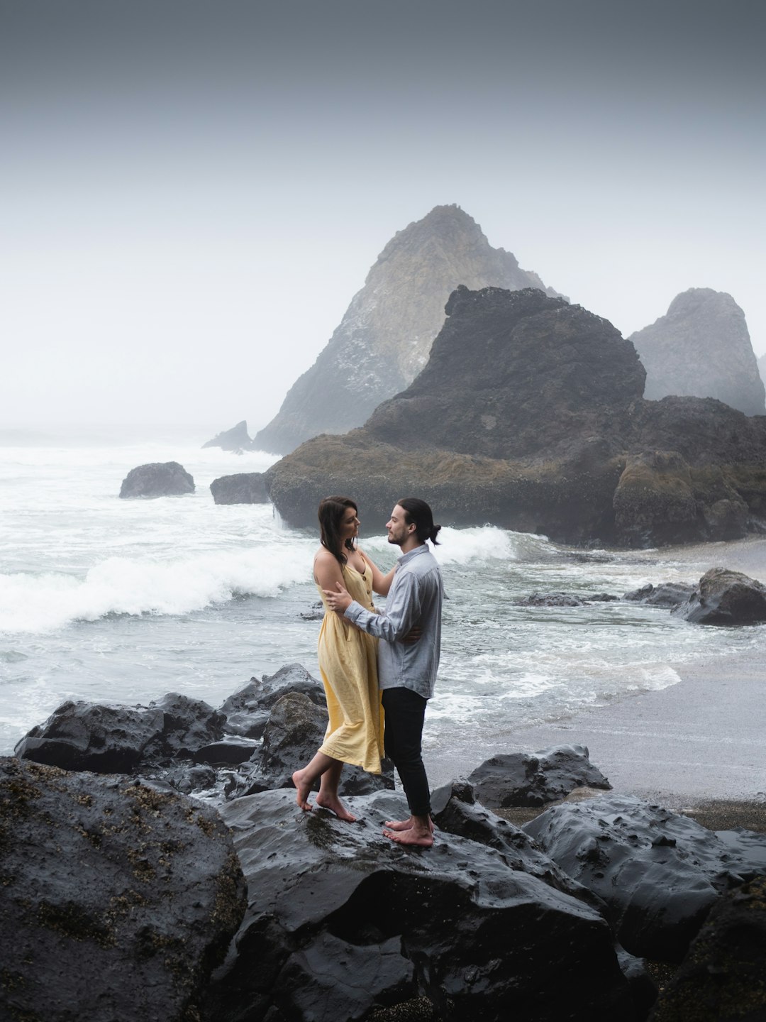 woman in white dress standing on rock formation near sea during daytime