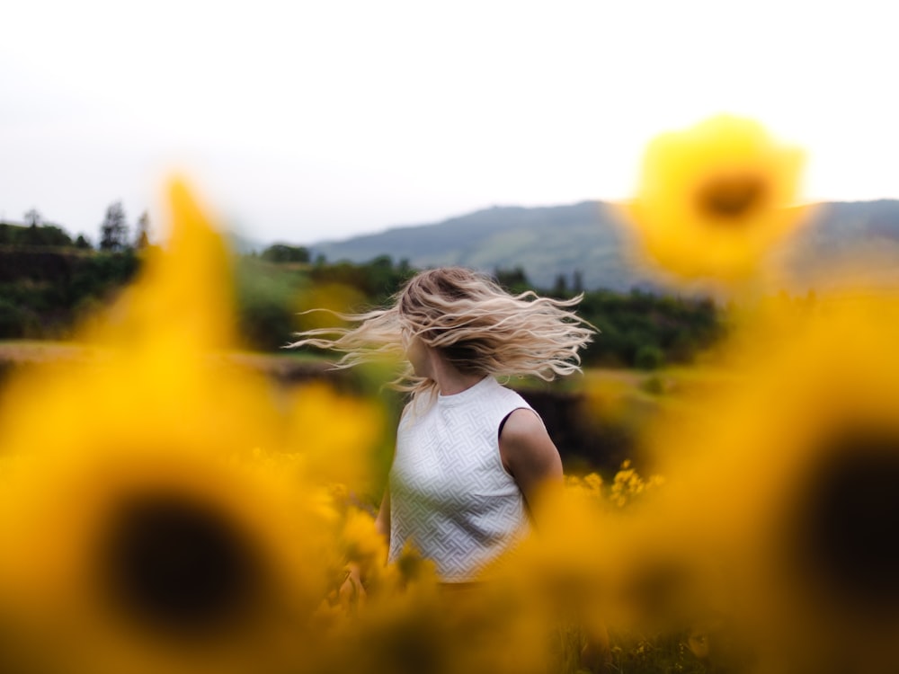 woman in white shirt standing on yellow flower field during daytime