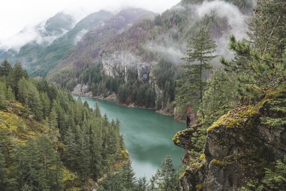 green lake surrounded by green trees and mountains during daytime