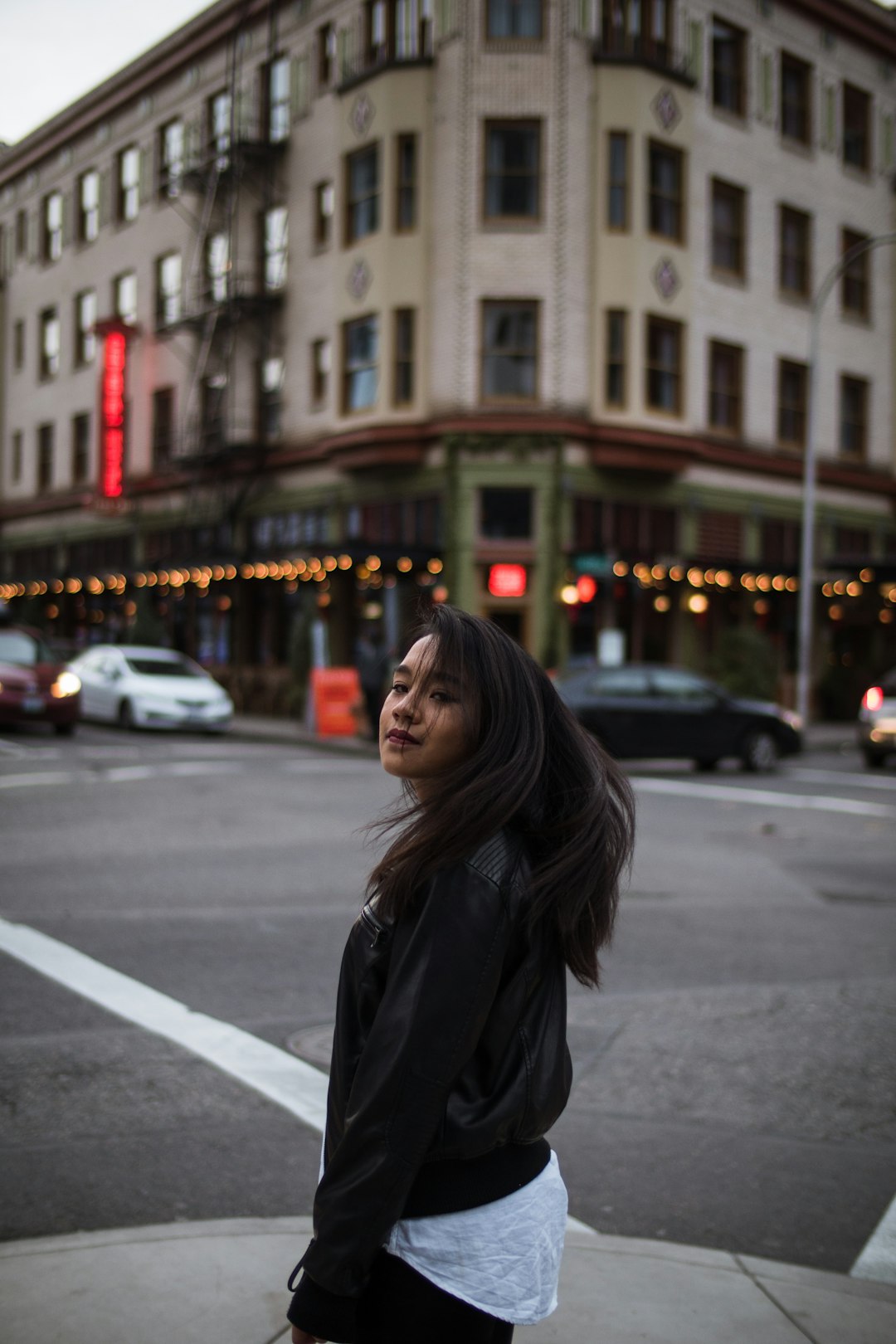 woman in black coat standing on the street during daytime