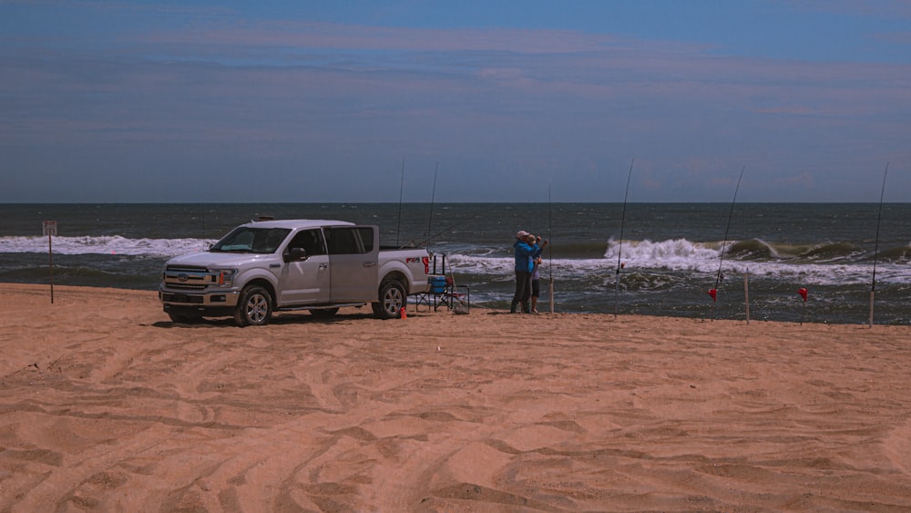 Weißer SUV auf braunem Sand in der Nähe von Gewässern tagsüber