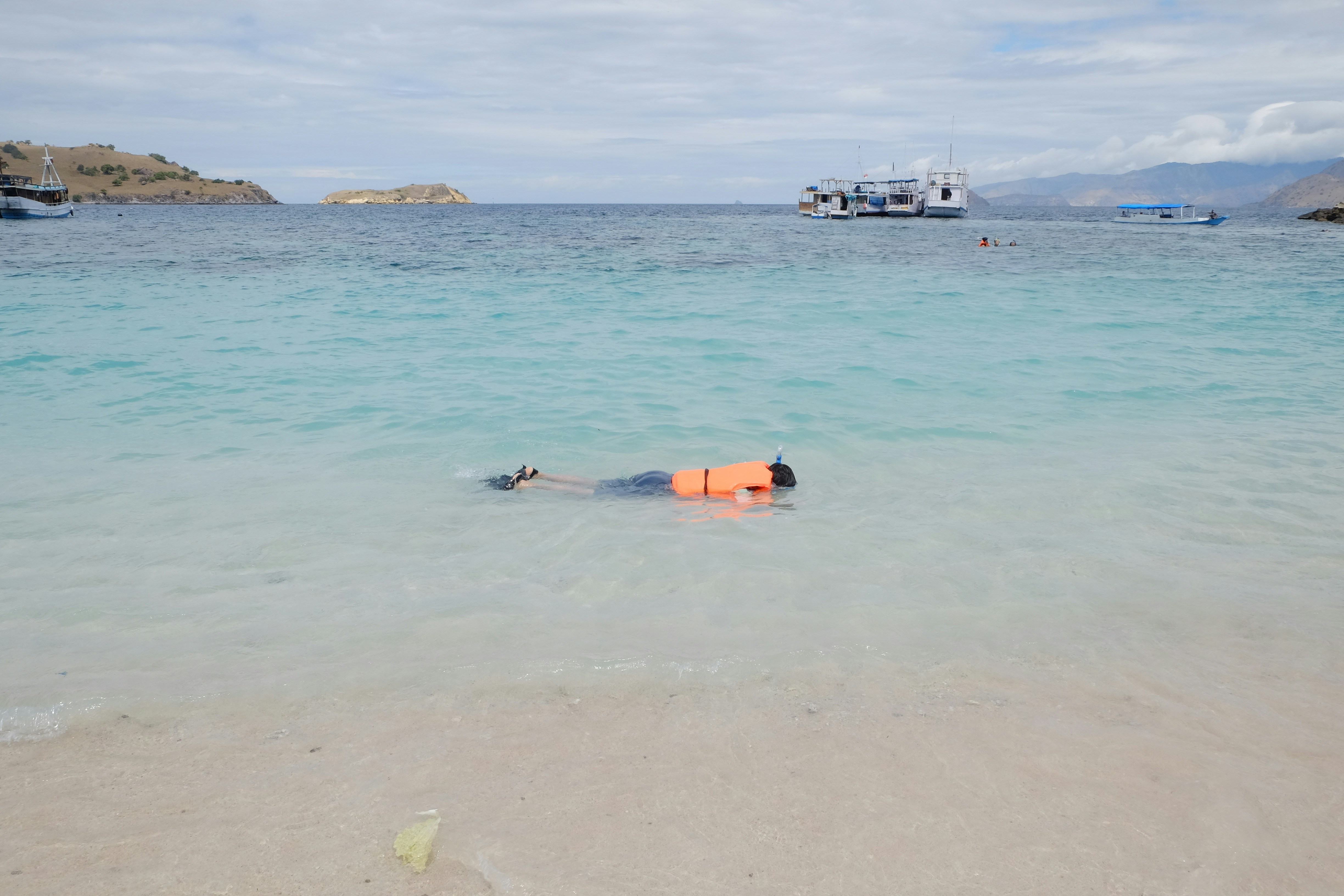 person in orange life vest on sea during daytime