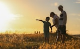 man and woman holding hands while walking on grass field during sunset