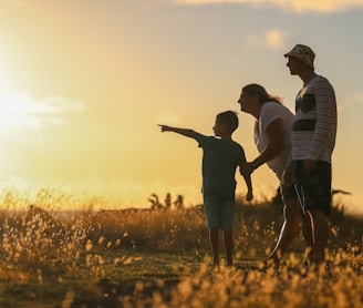 man and woman holding hands while walking on grass field during sunset