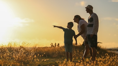 man and woman holding hands while walking on grass field during sunset