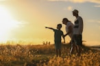 man and woman holding hands while walking on grass field during sunset