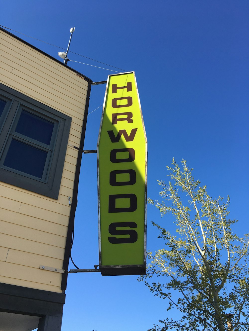 ein gelbes Schild, das an der Seite eines Gebäudes hängt