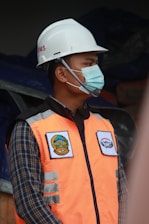 man in orange vest wearing white helmet