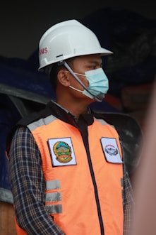 man in orange vest wearing white helmet