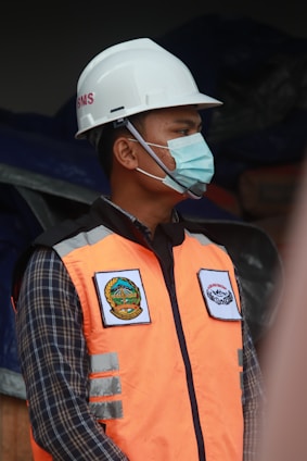 man in orange vest wearing white helmet
