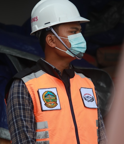 man in orange vest wearing white helmet