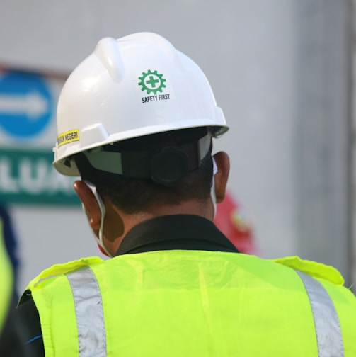 man in yellow and black vest wearing white helmet