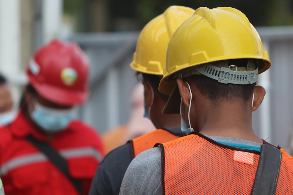 A construction worker in a yellow helmet and mask.