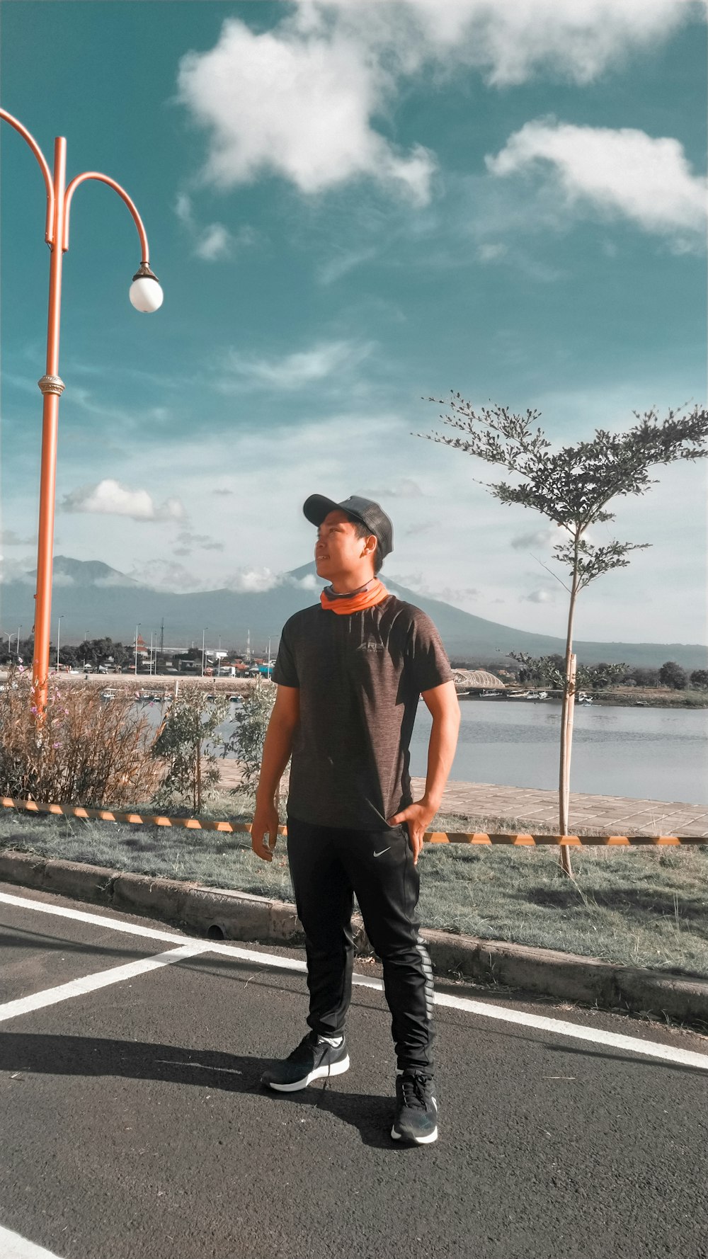 man in black crew neck t-shirt and black pants standing on gray asphalt road during