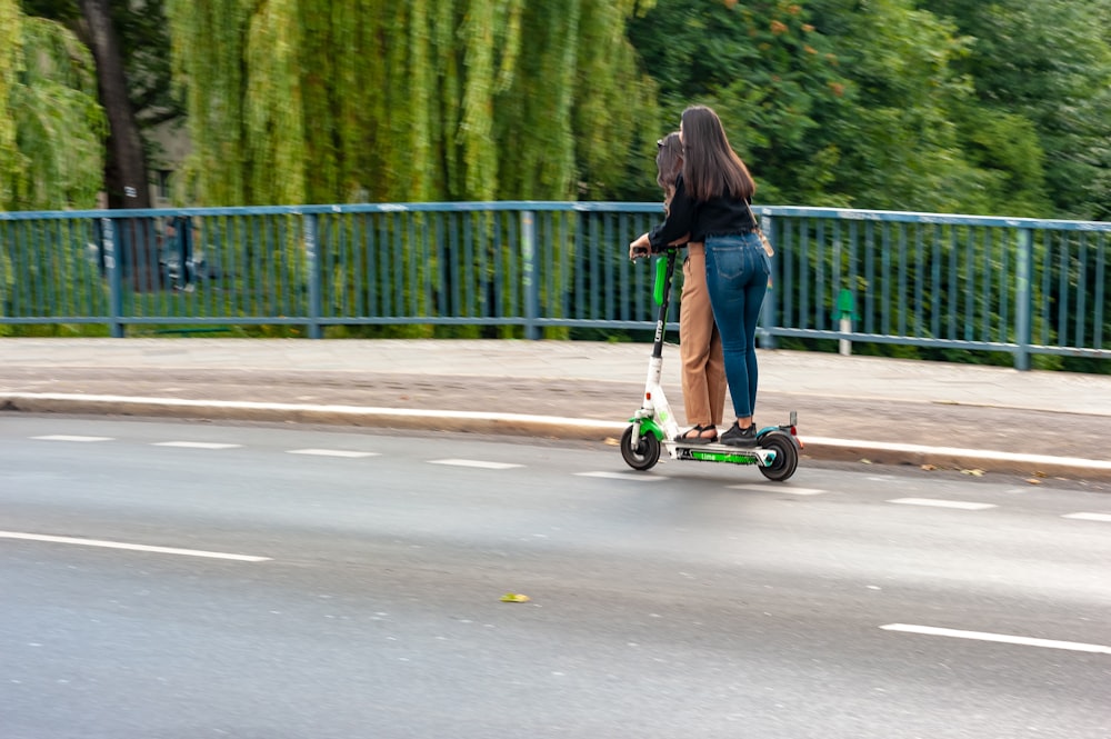 woman in black long sleeve shirt riding on black and red kick scooter on road during
