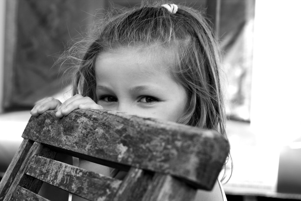 grayscale photo of girl sitting on wooden chair