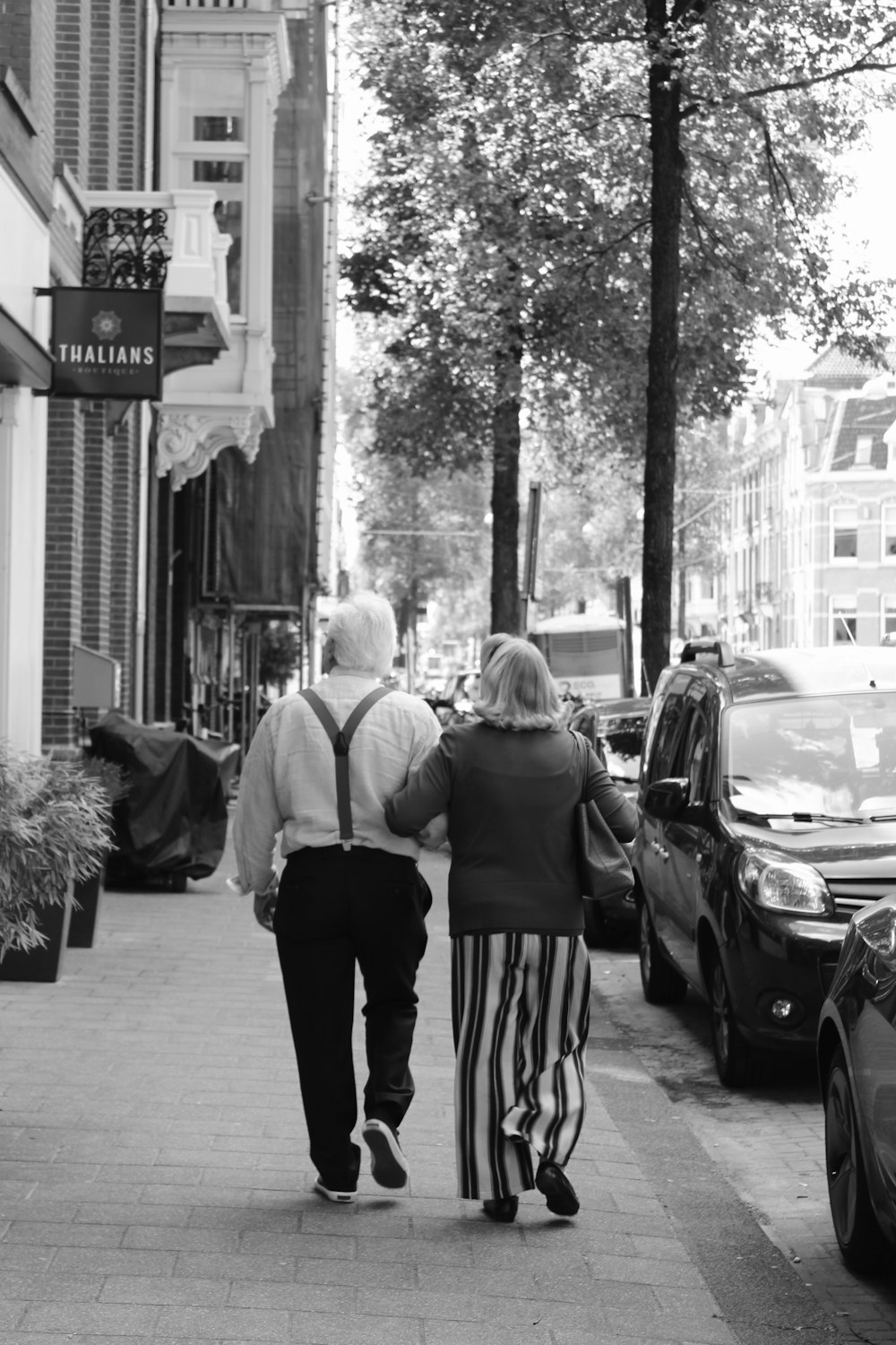 grayscale photo of 2 women walking on sidewalk
