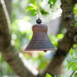 brown wooden bell hanging on tree during daytime