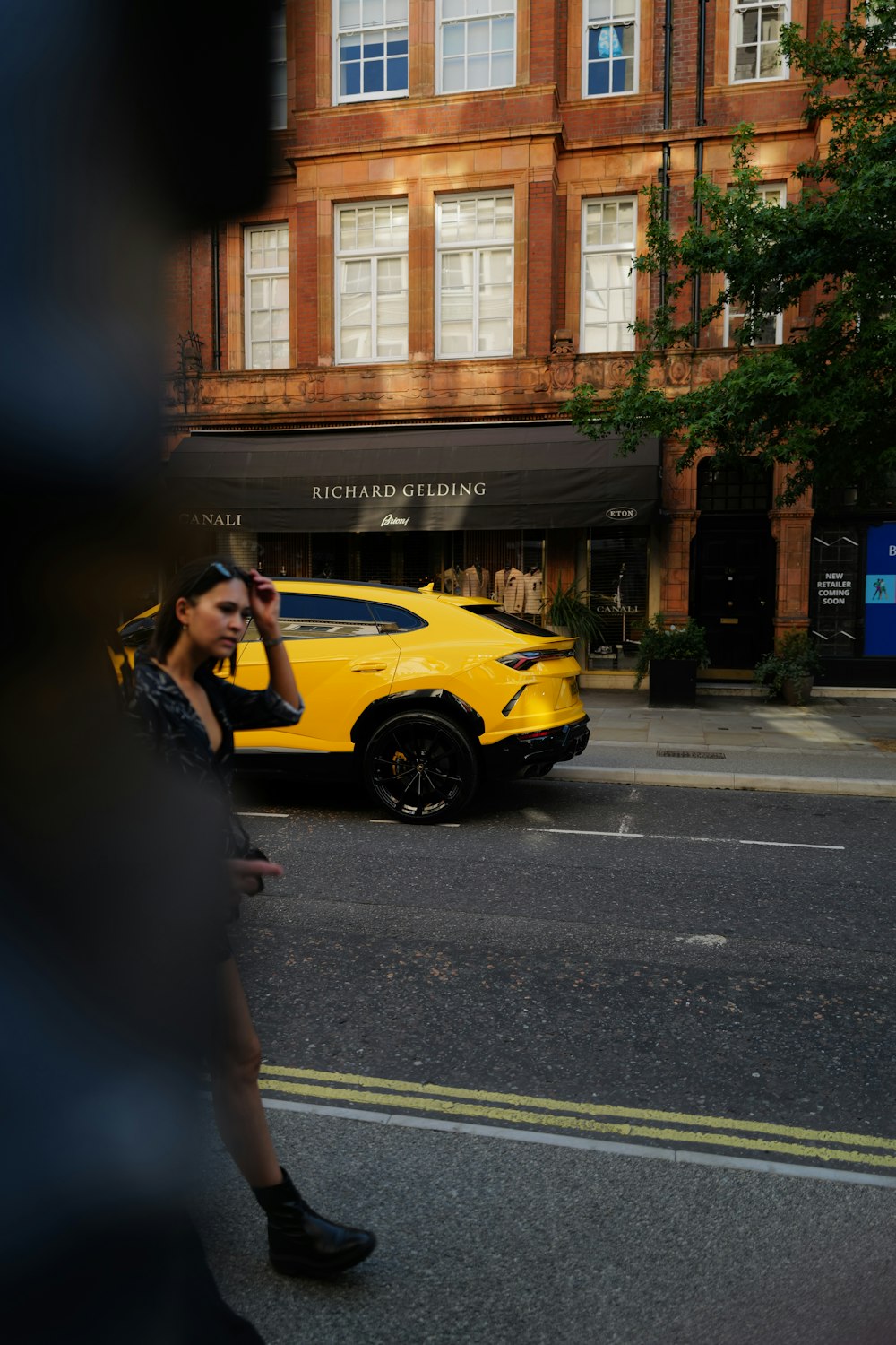 woman in black dress standing beside yellow car during daytime