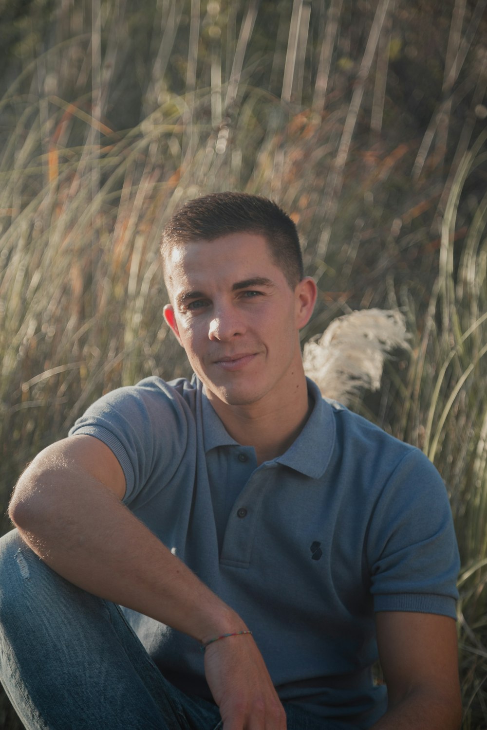 man in blue polo shirt sitting on brown grass during daytime