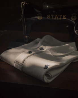 A neatly folded classic white shirt on a wooden table with soft natural lighting.