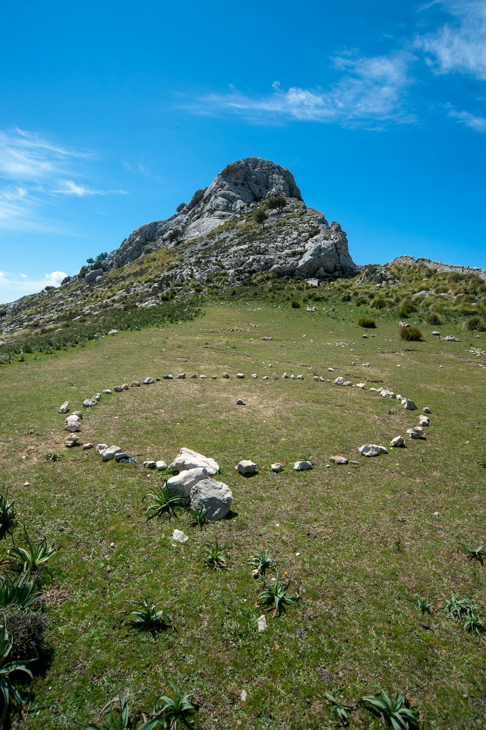 green grass field near mountain under blue sky during daytime