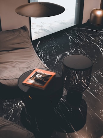 A sleek black leather pouf contrasting with light marble flooring in a contemporary Saudi living space.