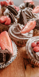 A rustic wooden table displaying a variety of gluten-free cupcakes with natural decorations