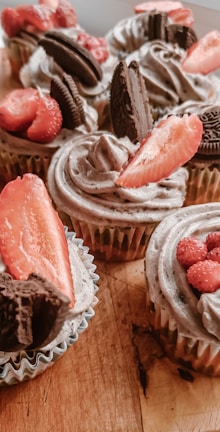 Assorted cupcakes arranged neatly on a rustic wooden table.
