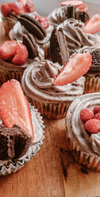 Assortment of colorful cupcakes with creamy frosting and sprinkles on a rustic wooden table