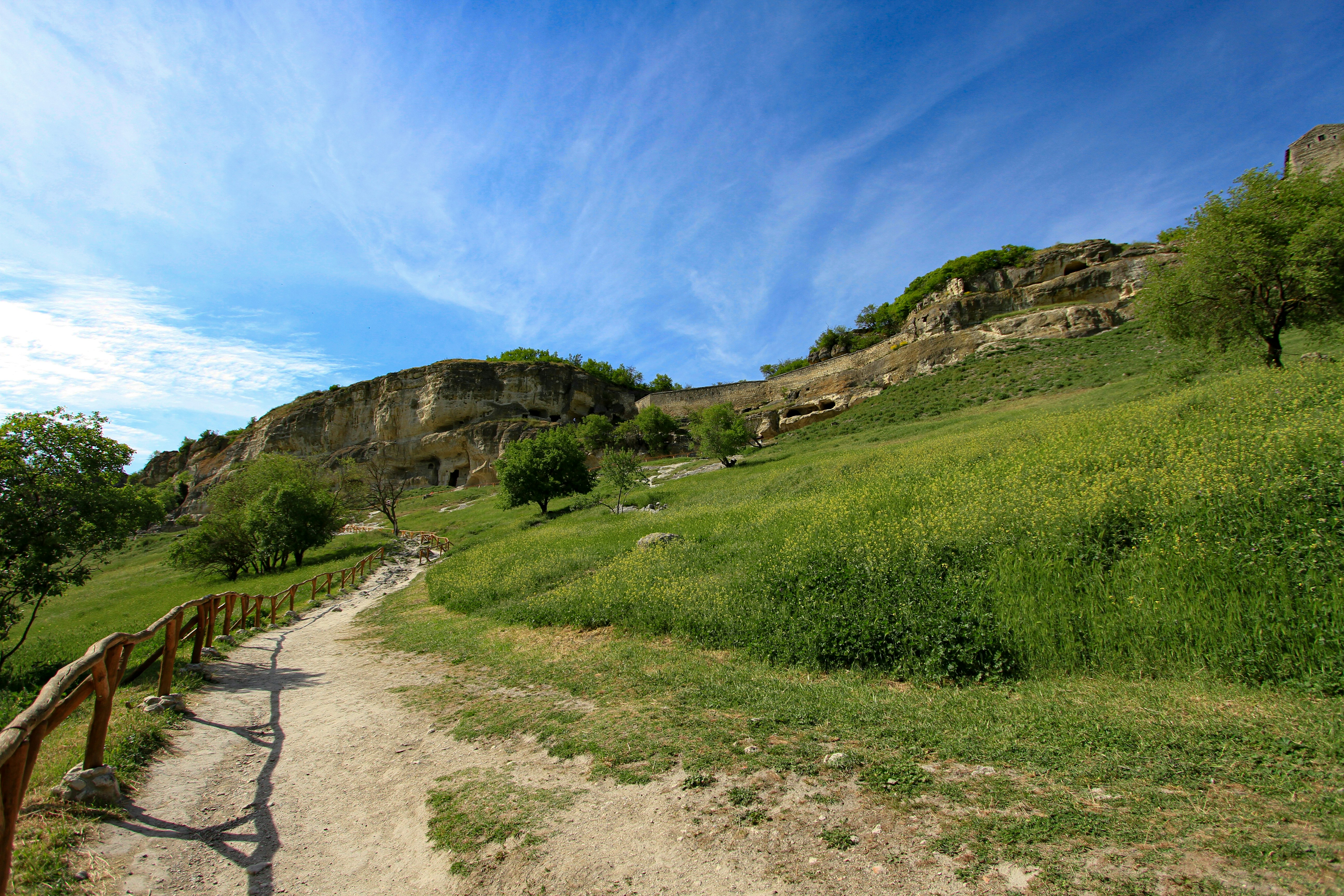 green grass field near mountain under blue sky during daytime