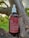 A brown glass bottle labeled 'kiara Pain Relief' is placed on a tree branch. The bottle has a white screw cap with a dropper. The label describes the contents as a full spectrum tincture, listing ingredients such as CBD and THC, along with usage instructions.