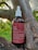 A brown glass bottle labeled 'kiara Pain Relief' is placed on a tree branch. The bottle has a white screw cap with a dropper. The label describes the contents as a full spectrum tincture, listing ingredients such as CBD and THC, along with usage instructions.